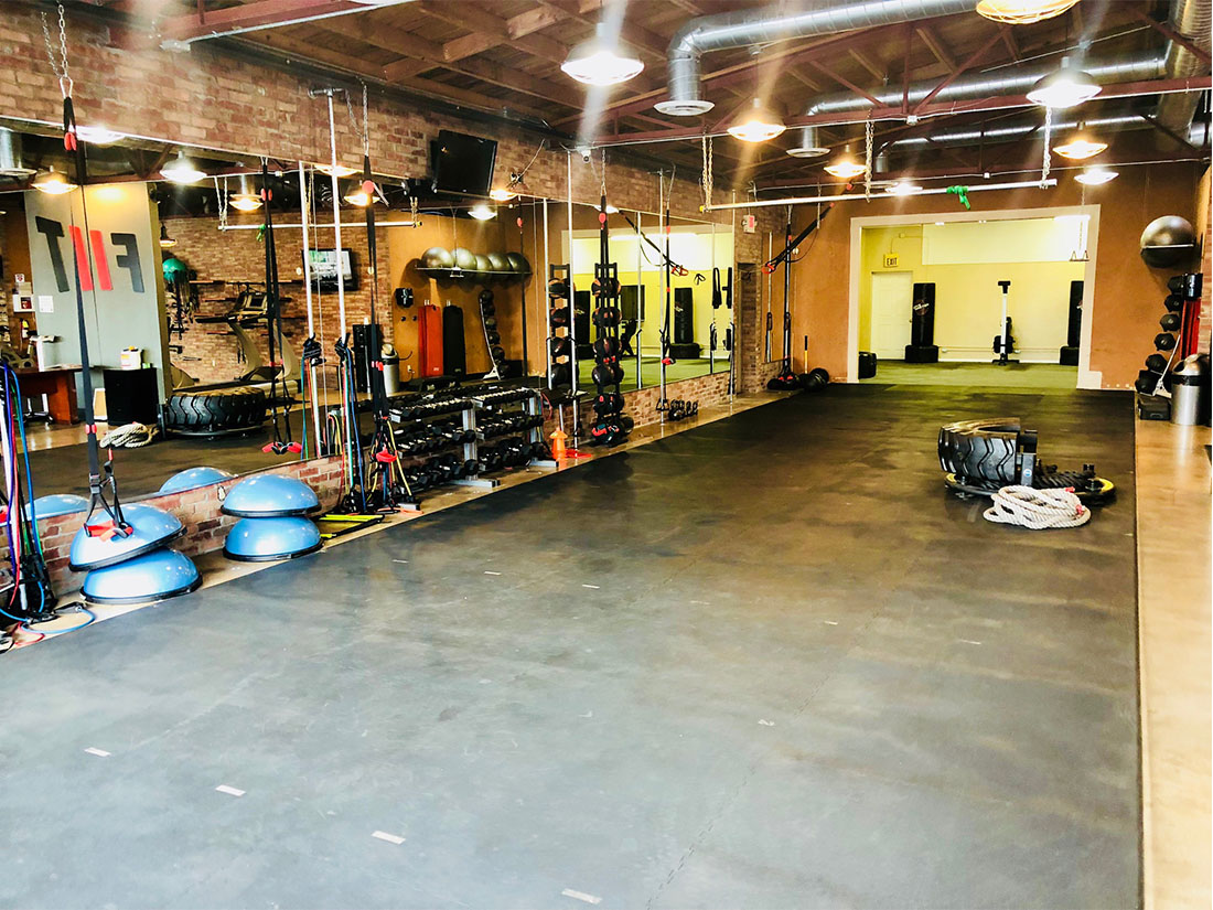 photo of FIIT by Jason Smith facility showing open space with bosu balls, dumbbell racks, TRX bands, battle ropes, agility ladder, resistance bands, tire flip and more to maximize weight loss and muscle gain